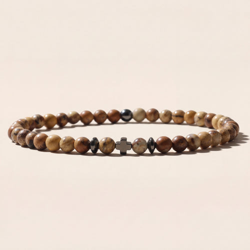 Beaded bracelet with a cross charm on a beige background