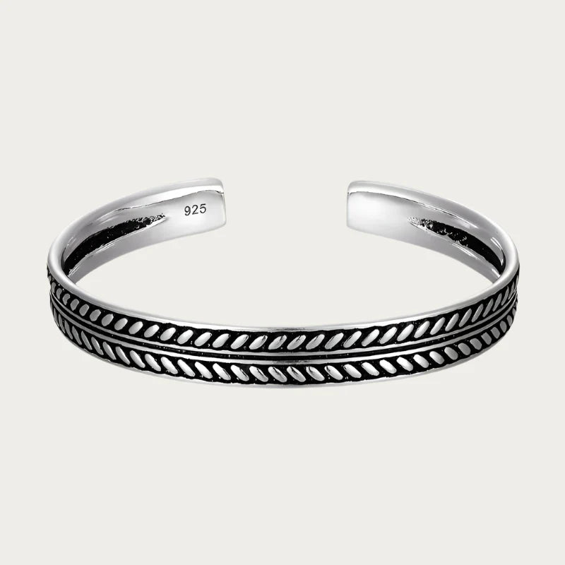 Silver cuff bracelet with engraved pattern and black details inspired by Brazilian craftsmanship.