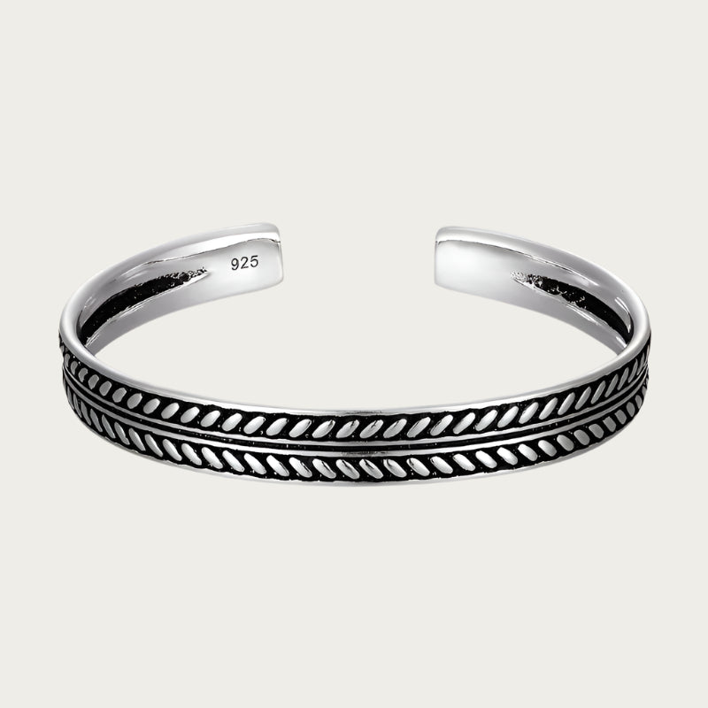 Silver cuff bracelet with engraved pattern and black details inspired by Brazilian craftsmanship.